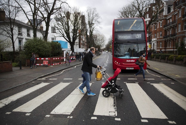 People walk over the zebra crossing where the cover picture of the Beatles' Abbey Road album was taken outside Abbey Road studios in London, Wednesday, March 9, 2016. George Martin, the Beatles' urbane producer who quietly guided the band's swift, historic transformation from rowdy club act to musical and cultural revolutionaries, has died, his management said Wednesday. He was 90. 