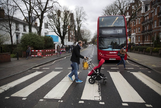 People walk over the zebra crossing where the cover picture of the Beatles' Abbey Road album was taken outside Abbey Road studios in London, Wednesday, March 9, 2016. George Martin, the Beatles' urbane producer who quietly guided the band's swift, historic transformation from rowdy club act to musical and cultural revolutionaries, has died, his management said Wednesday. He was 90.