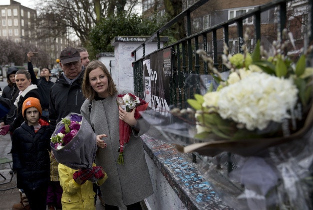 Tourists from Finland place flowers in memory of George Martin, the Beatles' producer, outside Abbey Road studios where the Beatles recorded albums and where the zebra crossing cover picture of the Abbey Road album was originally taken in London, Wednesday, March 9, 2016. George Martin, the Beatles' urbane producer who quietly guided the band's swift, historic transformation from rowdy club act to musical and cultural revolutionaries, has died, his management said Wednesday March 9, 2016. He was 90.