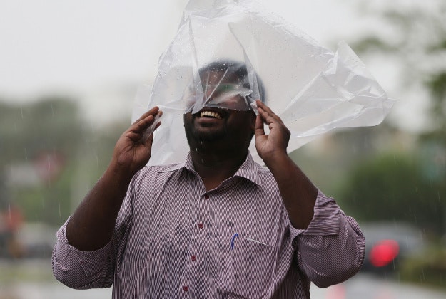 A man covering his head with a plastic bag enjoys walking under the rain in Dubai, United Arab Emirates, Wednesday, March 9, 2016. Heavy rains have closed Abu Dhabi's international airport and shut schools in the United Arab Emirates. 