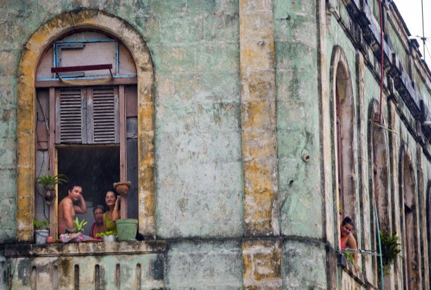 Local Cubans watch from their homes as the motorcade of U.S. President Barack Obama arrives in a section of Old Havana, Sunday, March 20, 2016 in Havana, Cuba. Obama became the first U.S. president to visit the island in nearly 90 years.