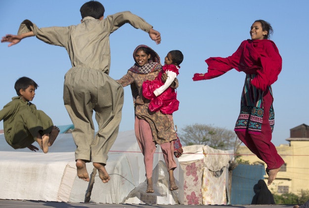 Pakistani children enjoy jumping on a trampoline, at a makeshift park in suburbs of Rawalpindi, Pakistan, Tuesday, March 22, 2016 