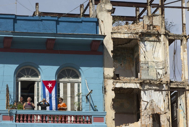 Local Cubans watch from their balcony as President Barack Obama's presidential motorcade departs the El Gran Teatro de Havana, after the president spoke, Tuesday, March 22, 2016, in Havana, Cuba.