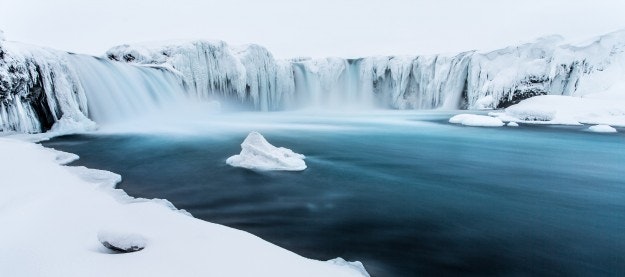 The is the famous Goðafoss in wintertime. Clear blue/green water and ice everywhere.