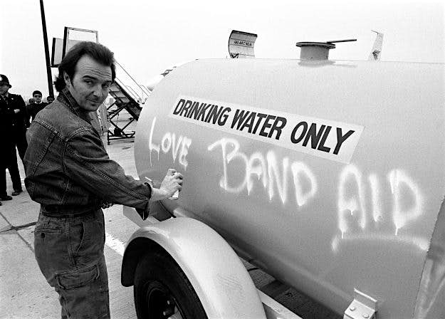 Travel News - Midge Ure - Do They Know It's Christmas? - Gatwick Airport - London Midge Ure, 31 of the Rock Group Ultravox, who with Bob Geldof wrote the Band Aid single 'Do They Know It's Christmas?', spraying a message on a water tanker at Gatwick Airport.