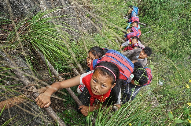 Pupils from Atuler village go home on a rattan ladder after school in Liangshan Yi Autonomous Prefecture, Sichuan Province of China.