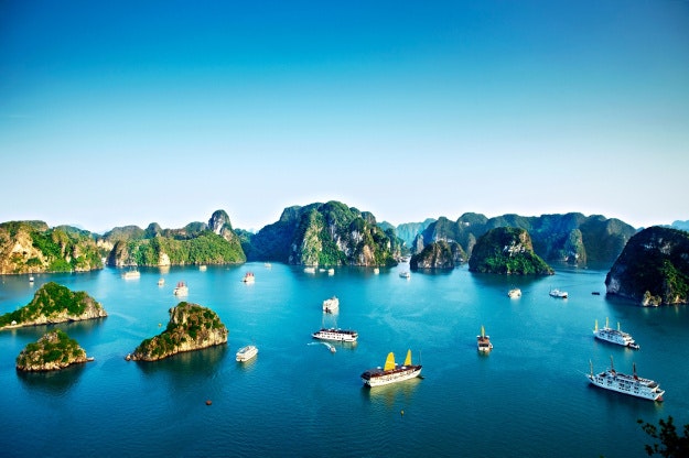 Chinese junks and cruise ships passing by limestone islands in Halong Bay. 