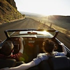 Travel News - Young couple driving convertible at sunset