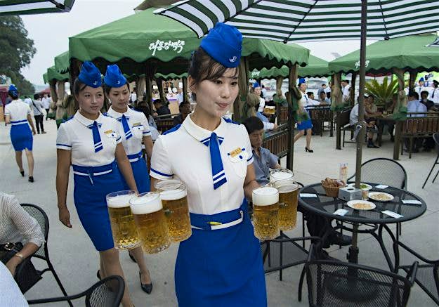 Travel News - NKOREA-FOOD-DRINK-BEER-FESTIVAL A waitress carries jugs of beer to guests before the opening of the Pyongyang Taedonggang Beer Festival on the banks of the Taedong river in Pyongyang
