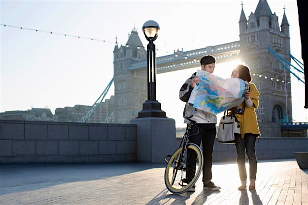 Travel News - couple-tourists-lost-map-directions-bicycle Young couple reading a map by Tower Bridge, London, England.