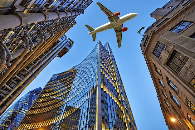 Travel News - airplane A jet plane flying low over a city.