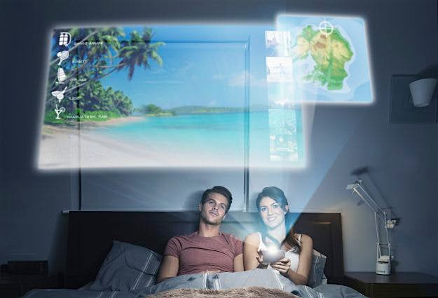 Travel News - Man and woman in bed looking at dream holiday on futuristic device In the future, guests could be making their online queries like this.