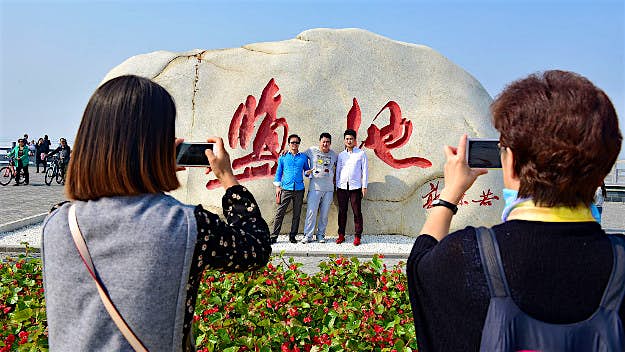 Travel News - GettyImages-611948002 Tourists take pictures at the colorful salt lake scenic spot on October 2, 2016 in Yuncheng, Shanxi Province of China. The salt lake displaying red and green colors in Yuncheng attract tourists during the National Day holiday. Formed about 500 million years ago, the salt lake owns different colors as a result of the algae in the water.