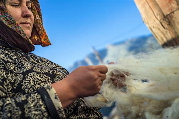 Travel News - Daily life in the highest village of Azerbaijan A woman cleaning and scratching sheep wool in her yard.