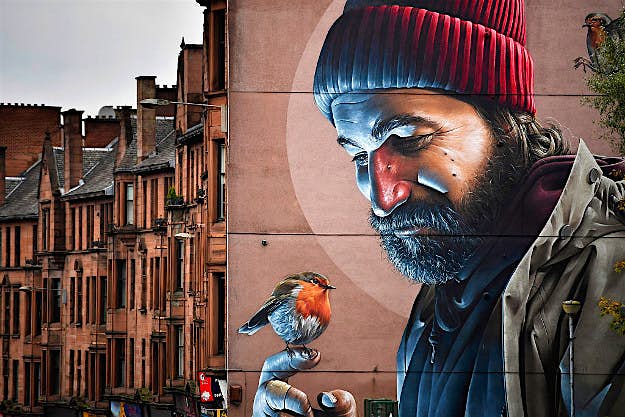 Travel News - gettyimages-618294142 Members of the public walk past one of the latest murals near Glasgow cathedral.