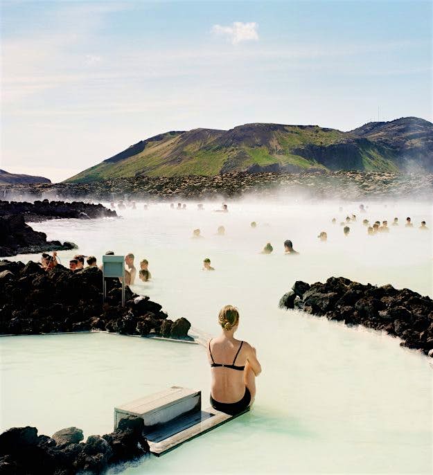 Travel News - Woman at blue lagoon Sitting on the edge of a Scandinavian geothermal blue lagoon is very hygge. Image: Muriel de Seze/Getty Images