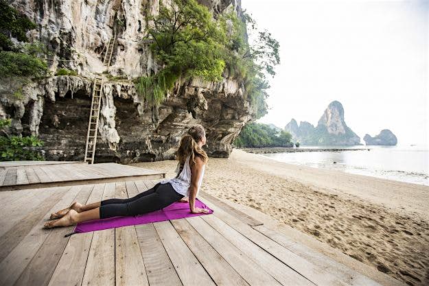 Travel News - A woman doing yoga. Your health is your wealth while you're travelling.