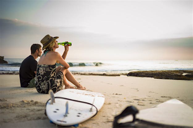 Travel News - #N/A Couple sitting on beach with surfboards, looking out to sea, Nusa Lembongan, Indonesia.