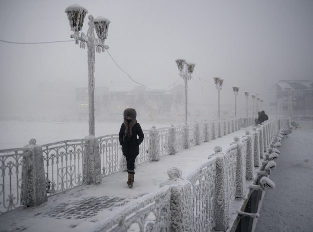 A woman walks over an ice-encrusted bridge in Yakutsk. Oymyakon lies a two day drive from the city of Yakutsk, the regional capital.