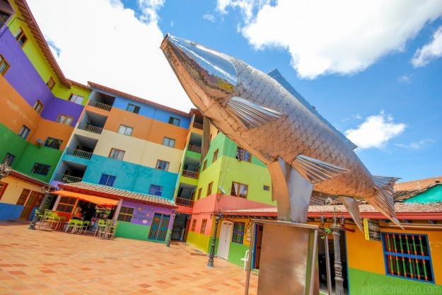 A sculpture seen amongst colourful houses.