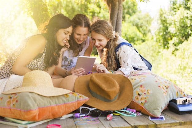 Travel News - Three teenage girls using digital tablet in tree house Three teenage girls using digital tablet in tree house