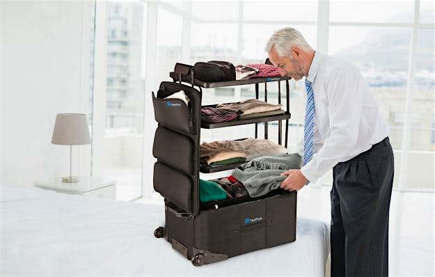 Travel News - Side view of a mature businessman unpacking luggage at a hotel bedroom ShelfPack