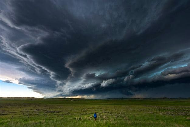 Travel News - storm1-8 A storm chaser stands in a field near Cheyenne, Wyoming watching a tornadic supercell approach.