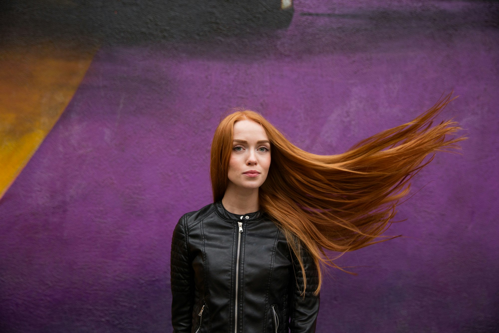 A redhead model Marina photographed in Moscow Russia in front of a purple mural
