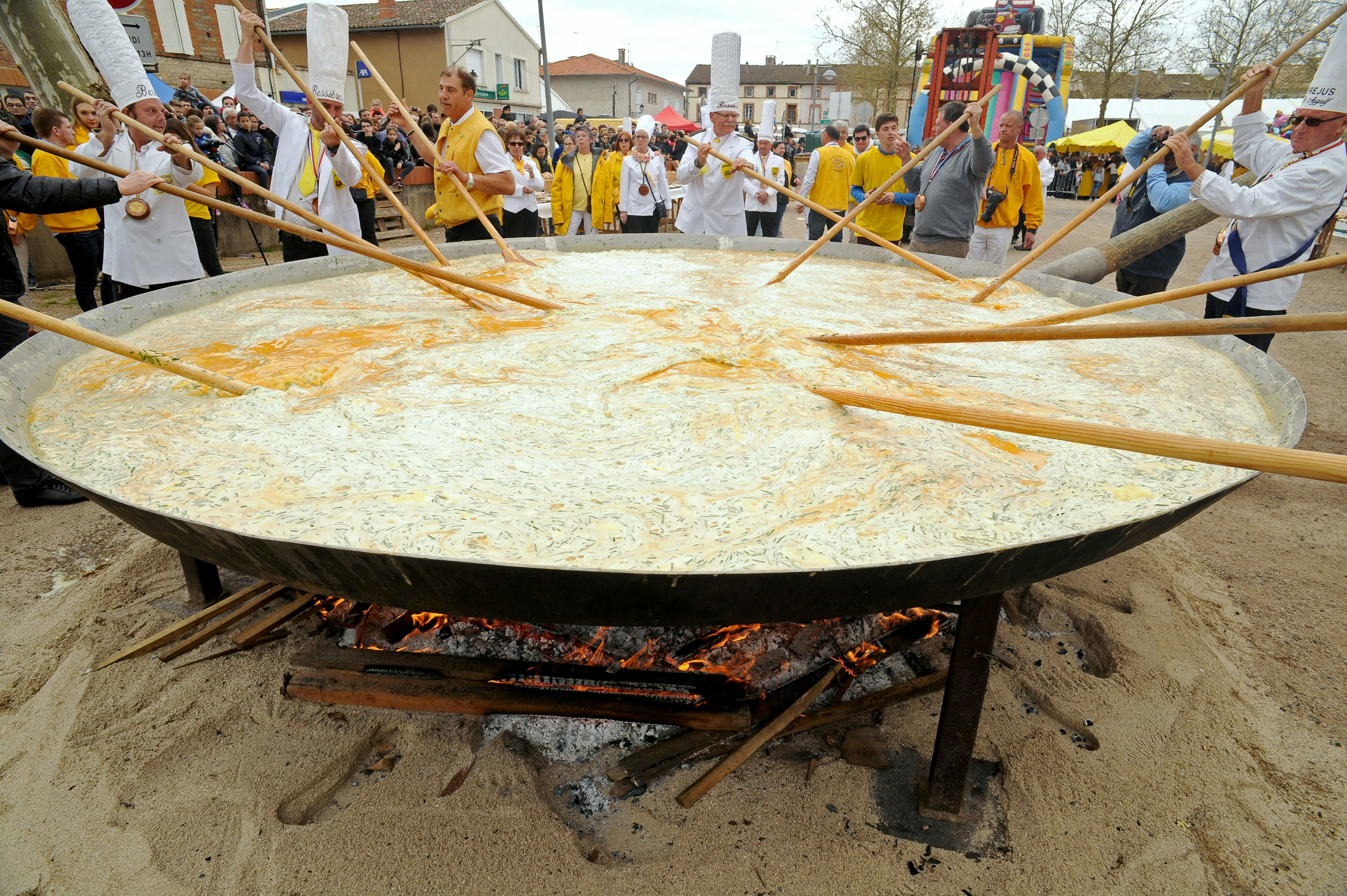Members of the Giant Omelette Brotherhood of Bessieres cook a giant omelette as part of Easter celebrations on March 28, 2016, on the main square of Bessieres, southern France. Over 15,000 eggs were used to make the omelette. / AFP / REMY GABALDA (Photo credit should read REMY GABALDA/AFP/Getty Images)