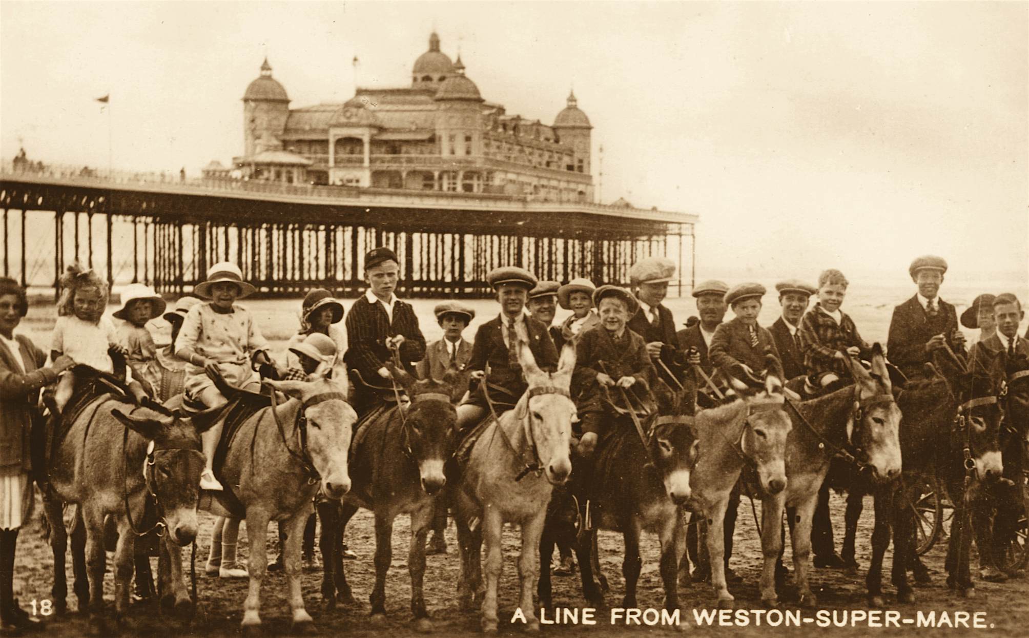 Travel News - UK Seaside Golden Era Children and donkeys on Weston-super-Mare Beach with the Grand Pier in the background, 1920s.