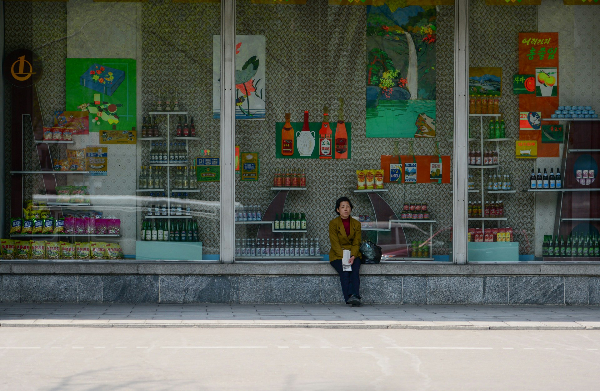 North Korean woman is relaxing on a storefront.