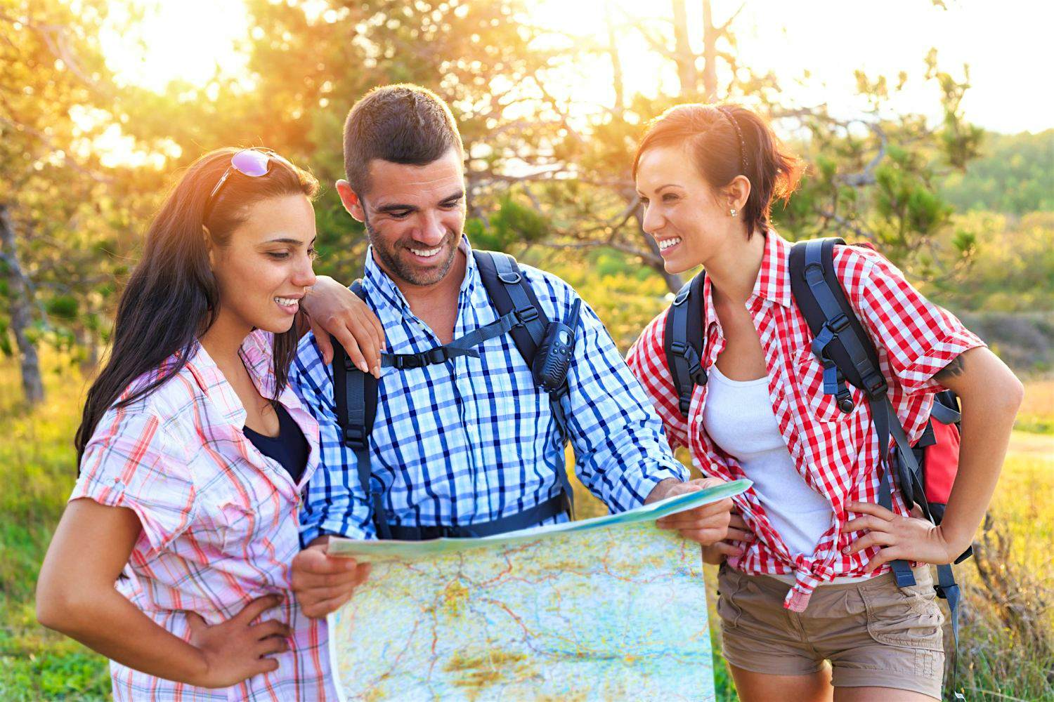 Travel News - Young people hiking and reading map Travel News - Young people hiking and reading map