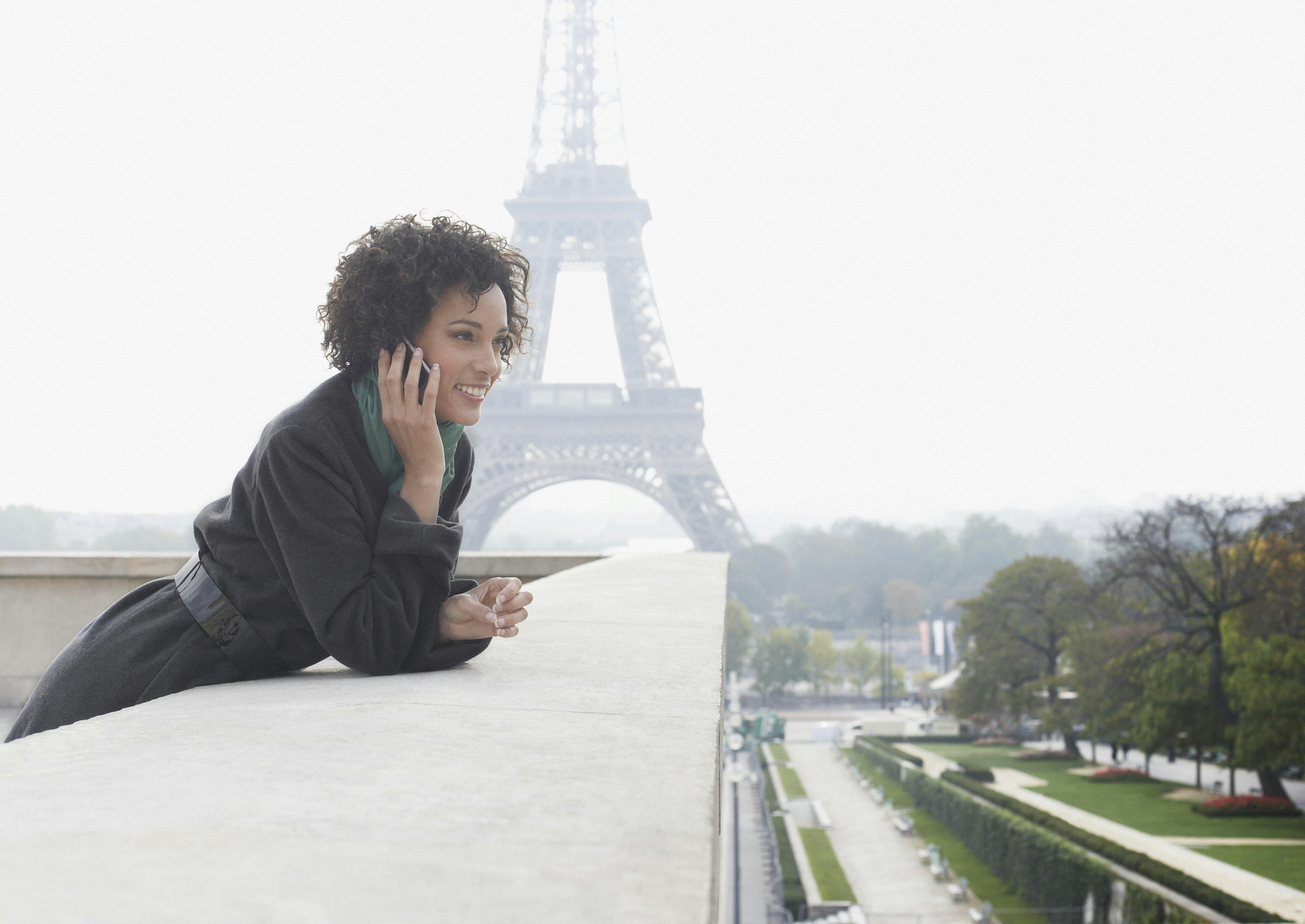 Woman outdoors on her mobile phone by the Eiffel Tower.