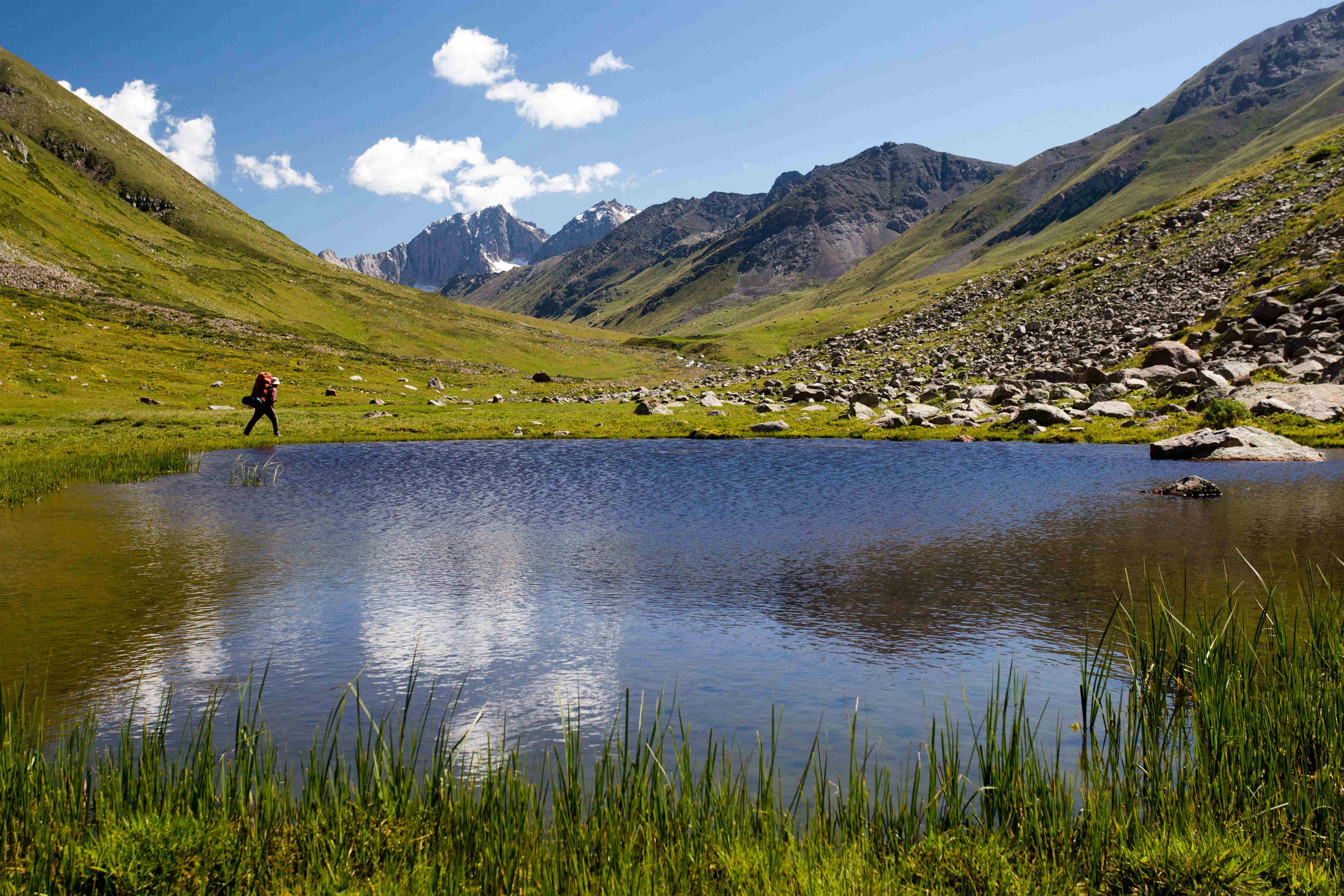 A trekker hikes along a lake in Kyrgyzstan.