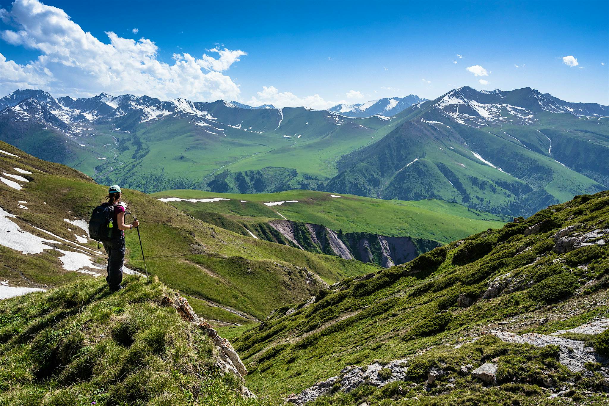 Travel News - Jarryd Salem A person hikes on high hills in the mountains of Kyrgyzstan.