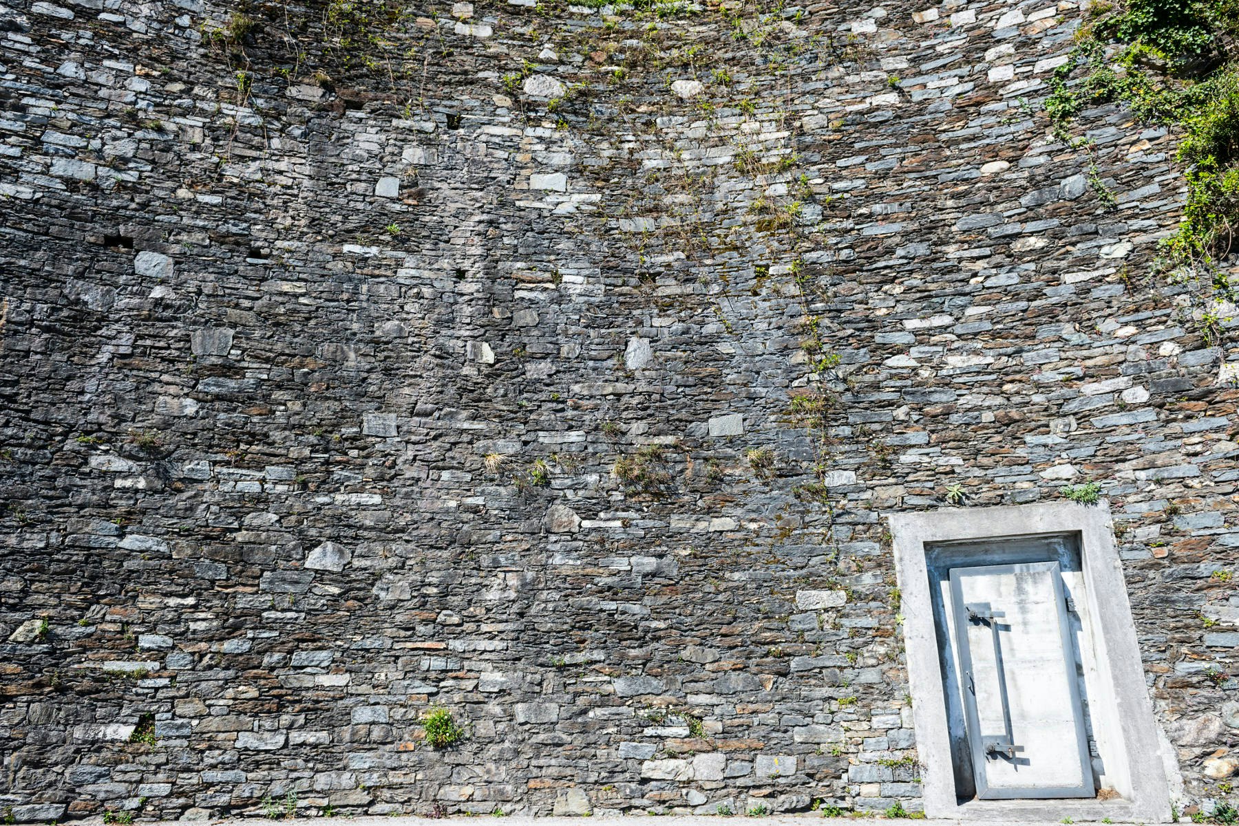 Bunker door and stone wall in Ticino, Switzerland.