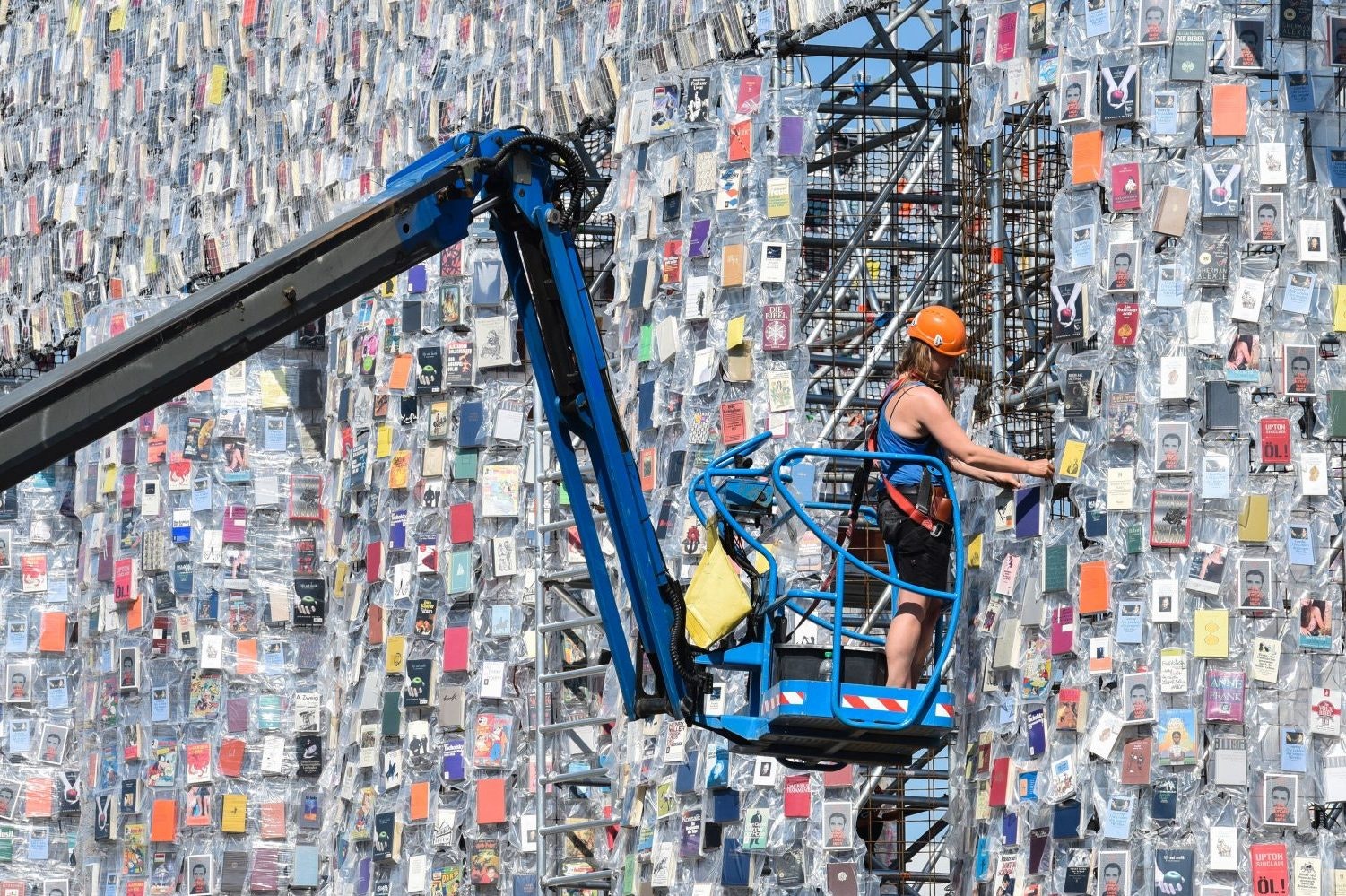 A volunteer uses a mobile lift to hang books on the "Parthenon of Books" by Argentinian artist Marta Minujin. Image: John MacDougall/AFP/Getty Images