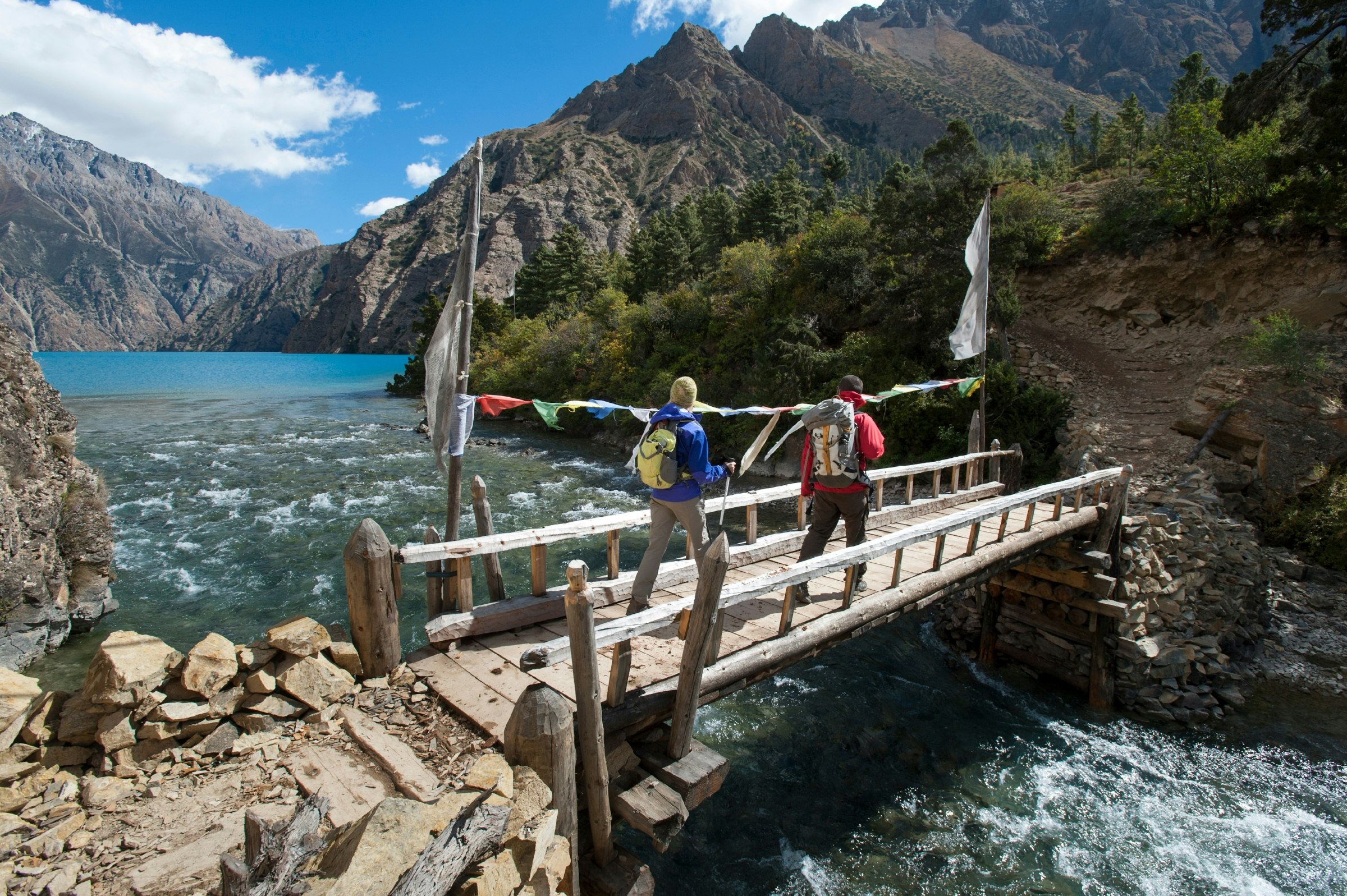 A couple of hikers admire the spectacular blue of Phoksundo lake while crossing a bridge in Dolpa, a remote region of Nepal