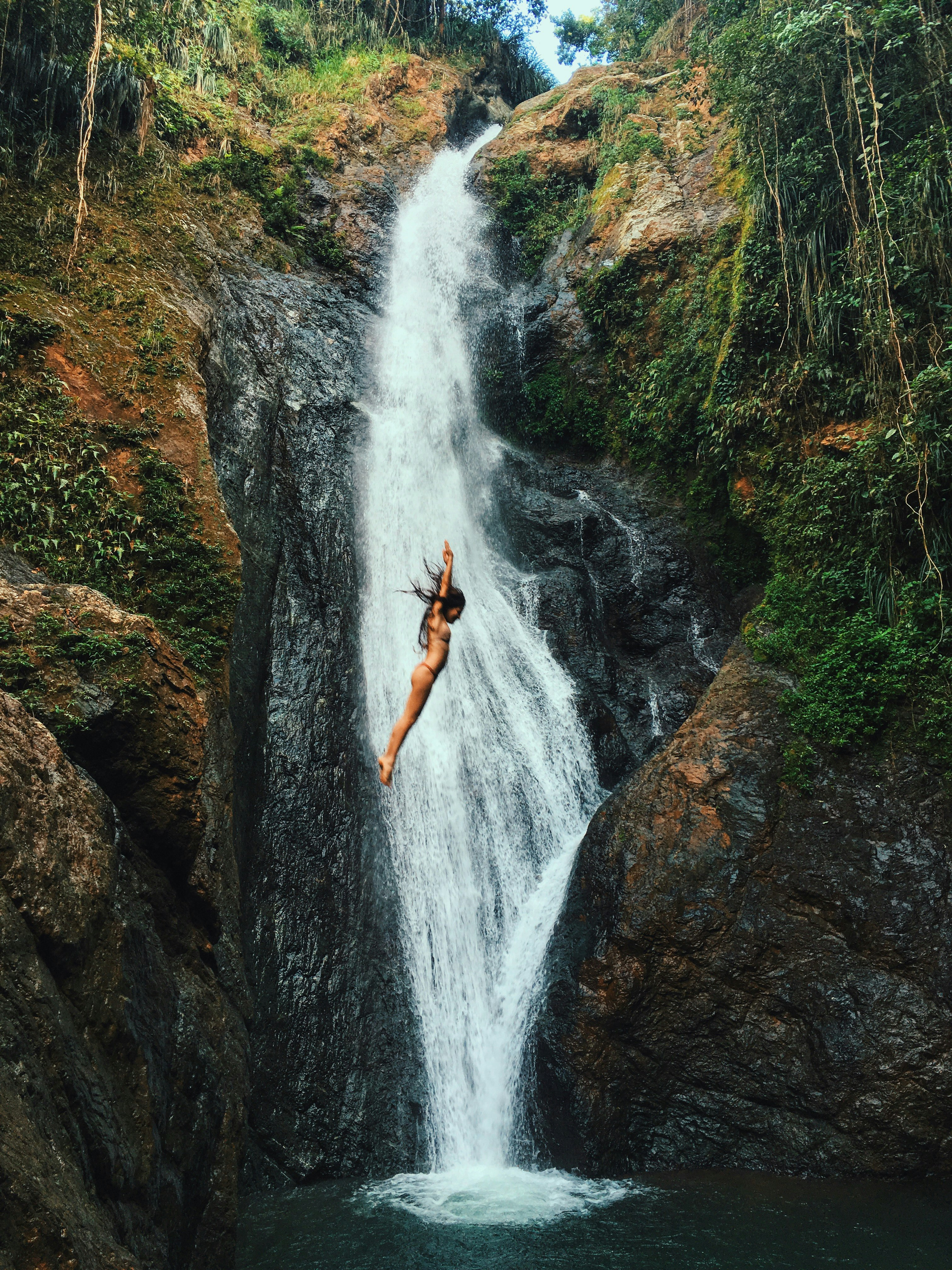 Woman jumps into a waterfall