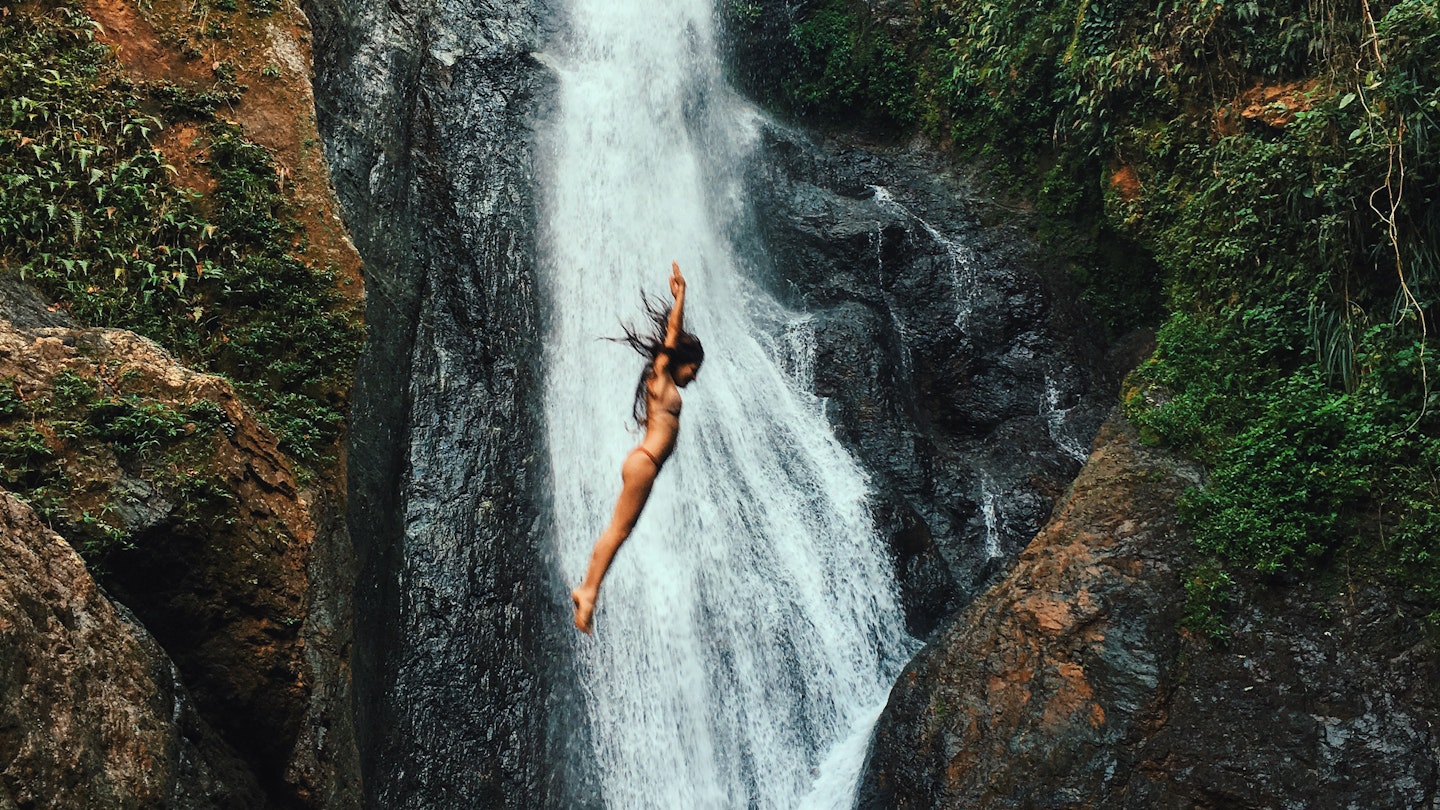 Woman jumps into a waterfall