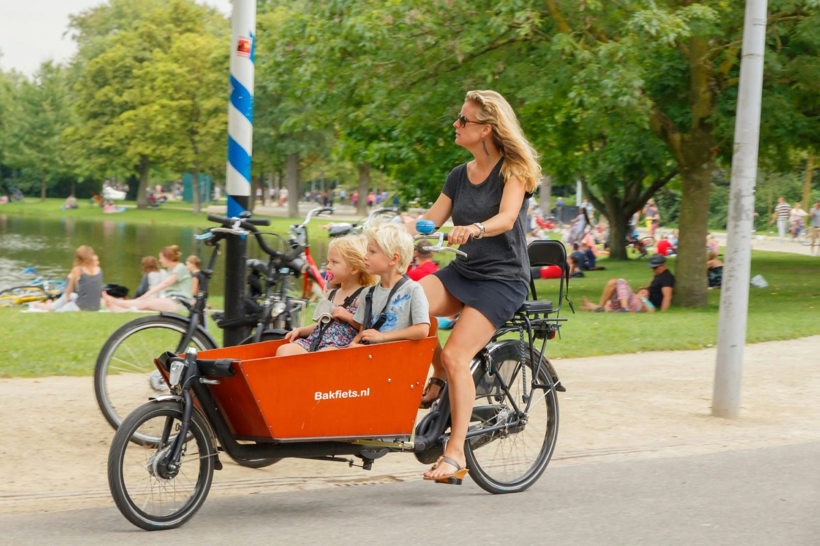 A woman cycling a cargo bike with children in Amsterdam.