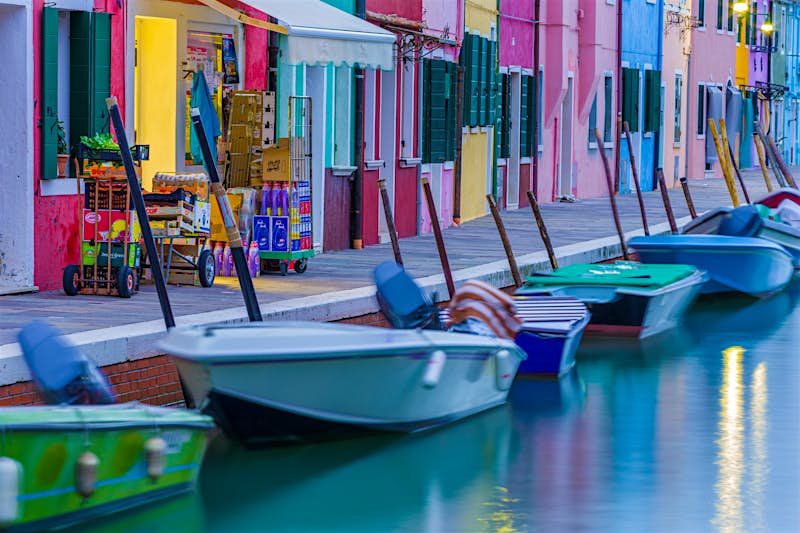 Travel News - Boats moored in a canal, Canali Di Venezia, Burano, Venetian Lagoon, Venice, Veneto, Italy This website gives you tips for sustainable travel in Venice. Image by SuperStock