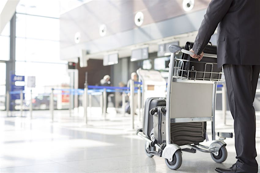 Travel News - Businessman with baggage cart at the airport Travel News - Businessman with baggage cart at the airport