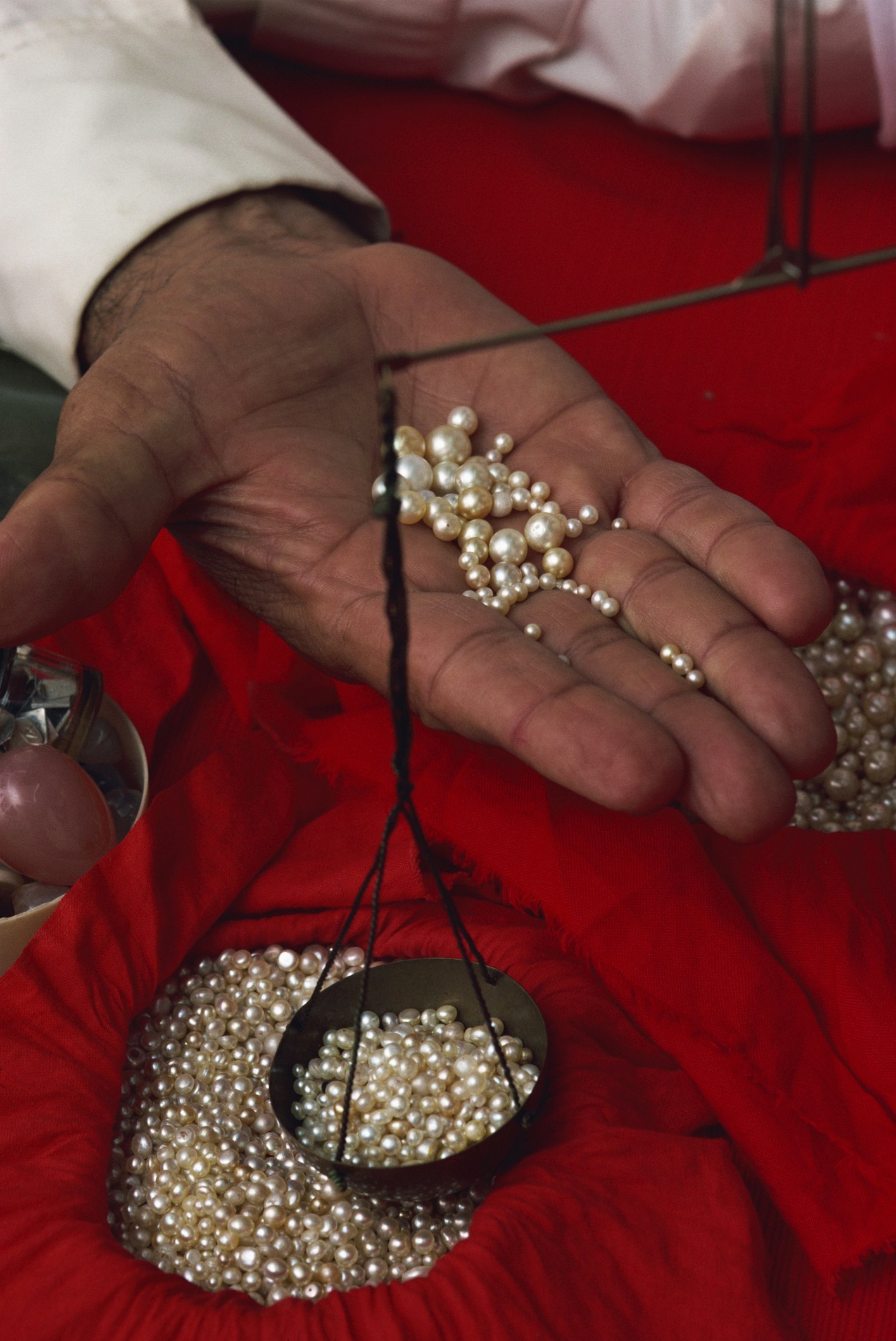 Travel News - Close-up of hand displaying pearls with weighing scales, in the pearl souk, Manama, Bahrain, Middle East