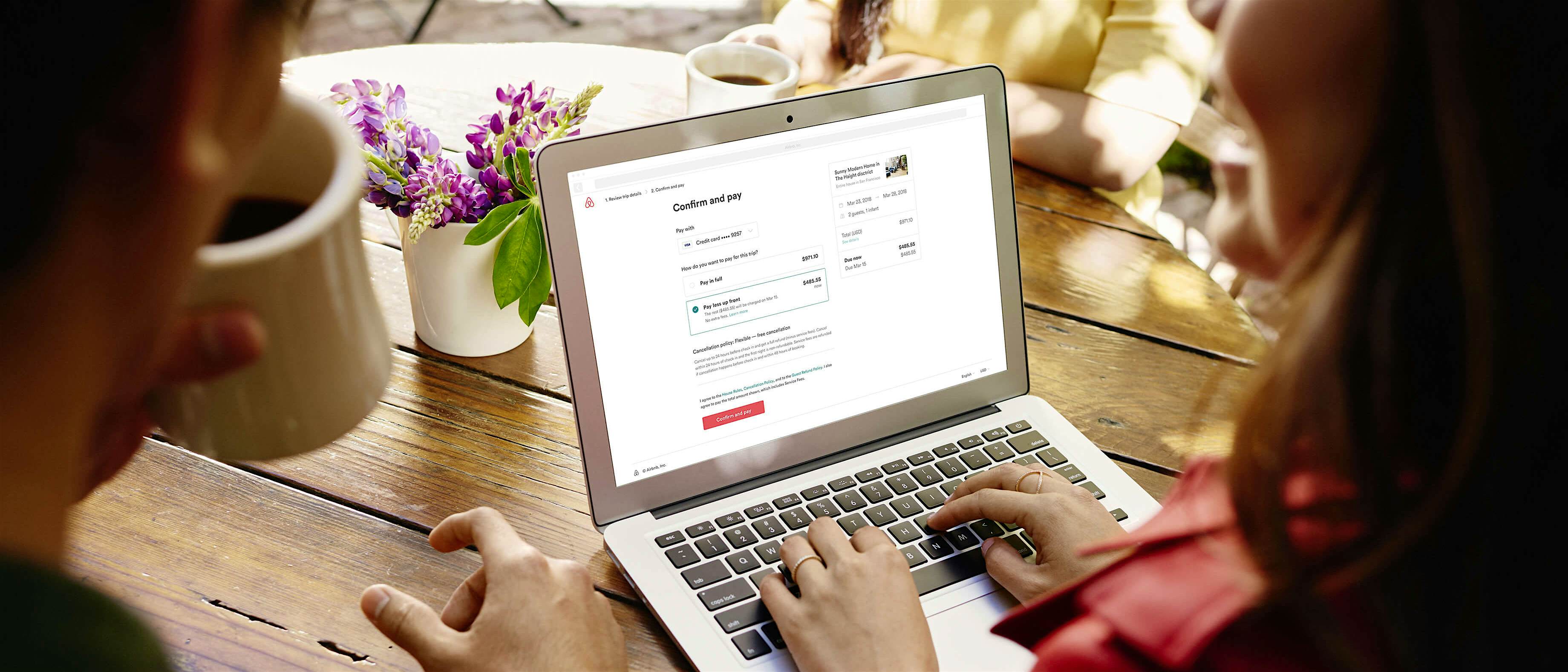 Travel News - pay less up front A couple books an Airbnb on a laptop.