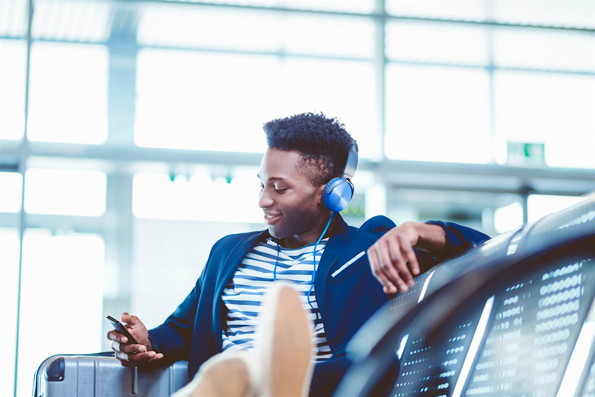 Travel News - Young man listening to music airport The band has used their extensive knowledge of world music to generate unique playlists based on destinations.