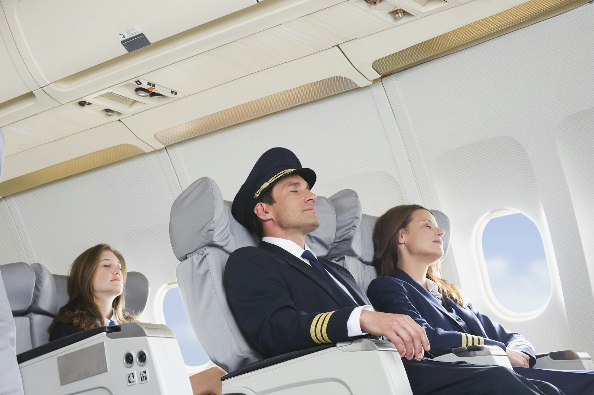Travel News - Germany, Bavaria, Munich, Mid adult flight personnels and stewardess resting in business class airplane cabin