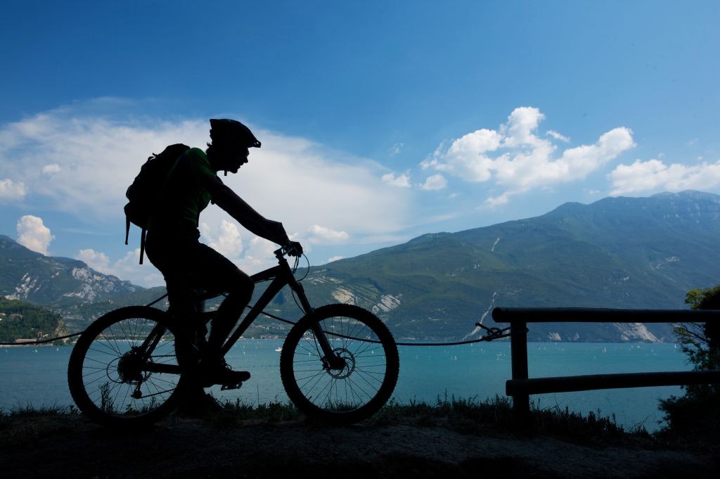 Travel News - Mountain bike rider with Garda lake in the background. Trentino Alto Adige. Italy. Europe