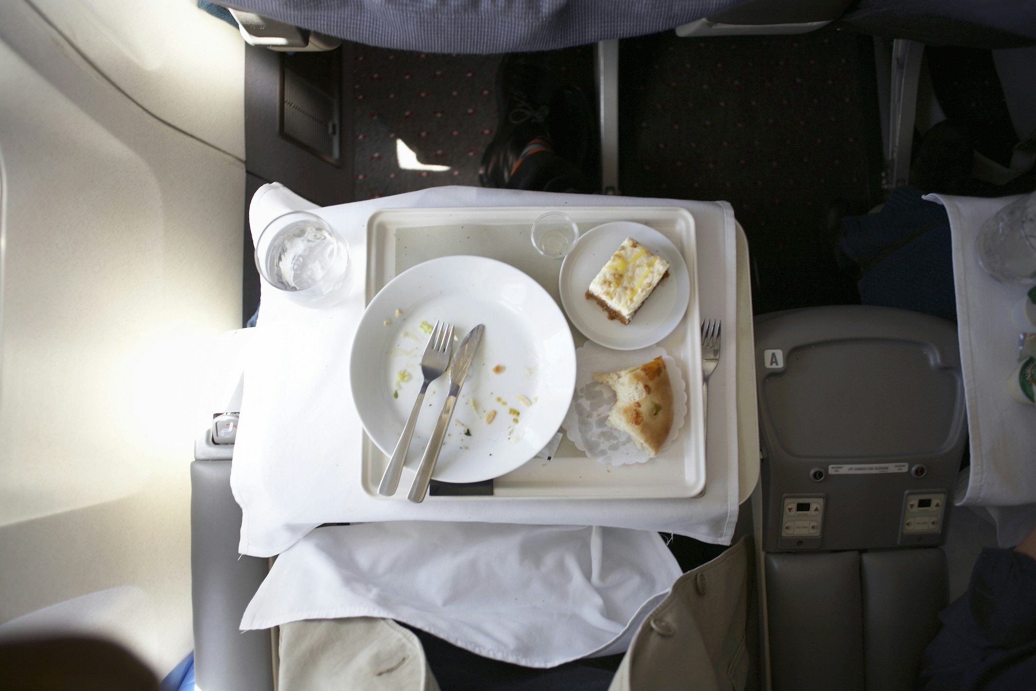 Travel News - Plate and cutlery on tray table in airplane, overhead view