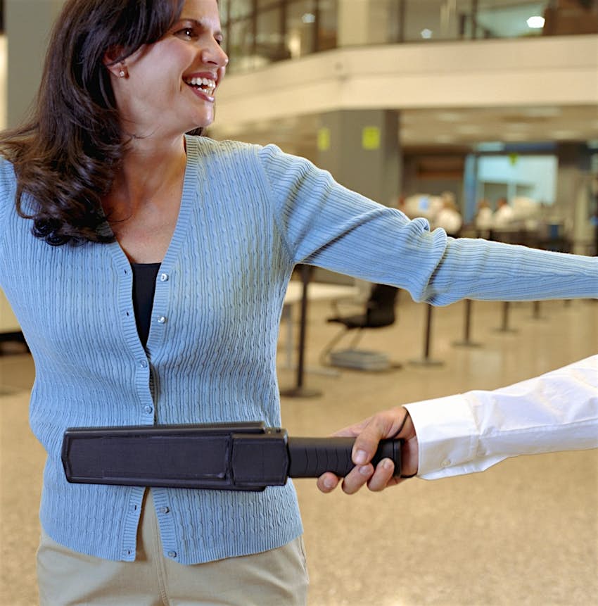 Travel News - Woman being swiped by metal detector at airport security checkpoint Travel News - Woman being swiped by metal detector at airport security checkpoint